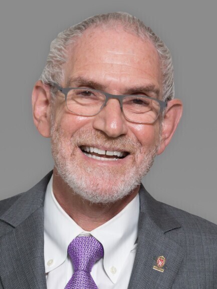 headshot of a white man with short white hair and glasses