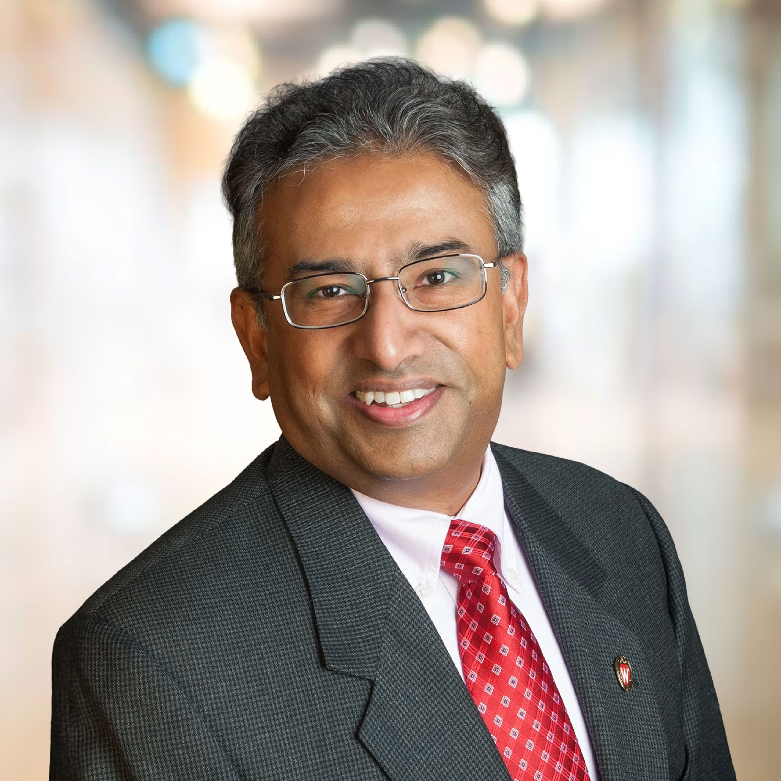 headshot of a south asian man with short gray hair and glasses