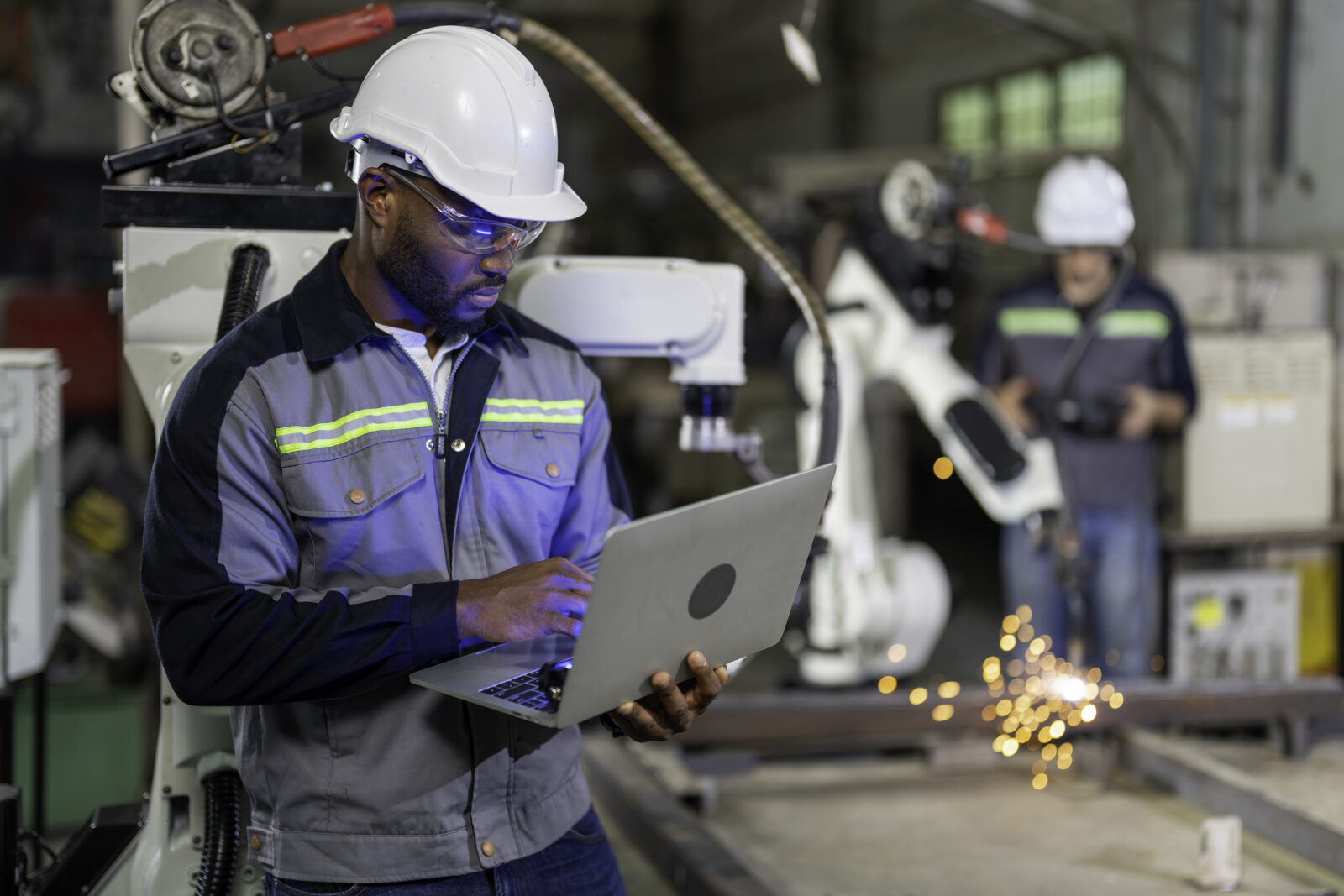 man working in a factory holding a computer
