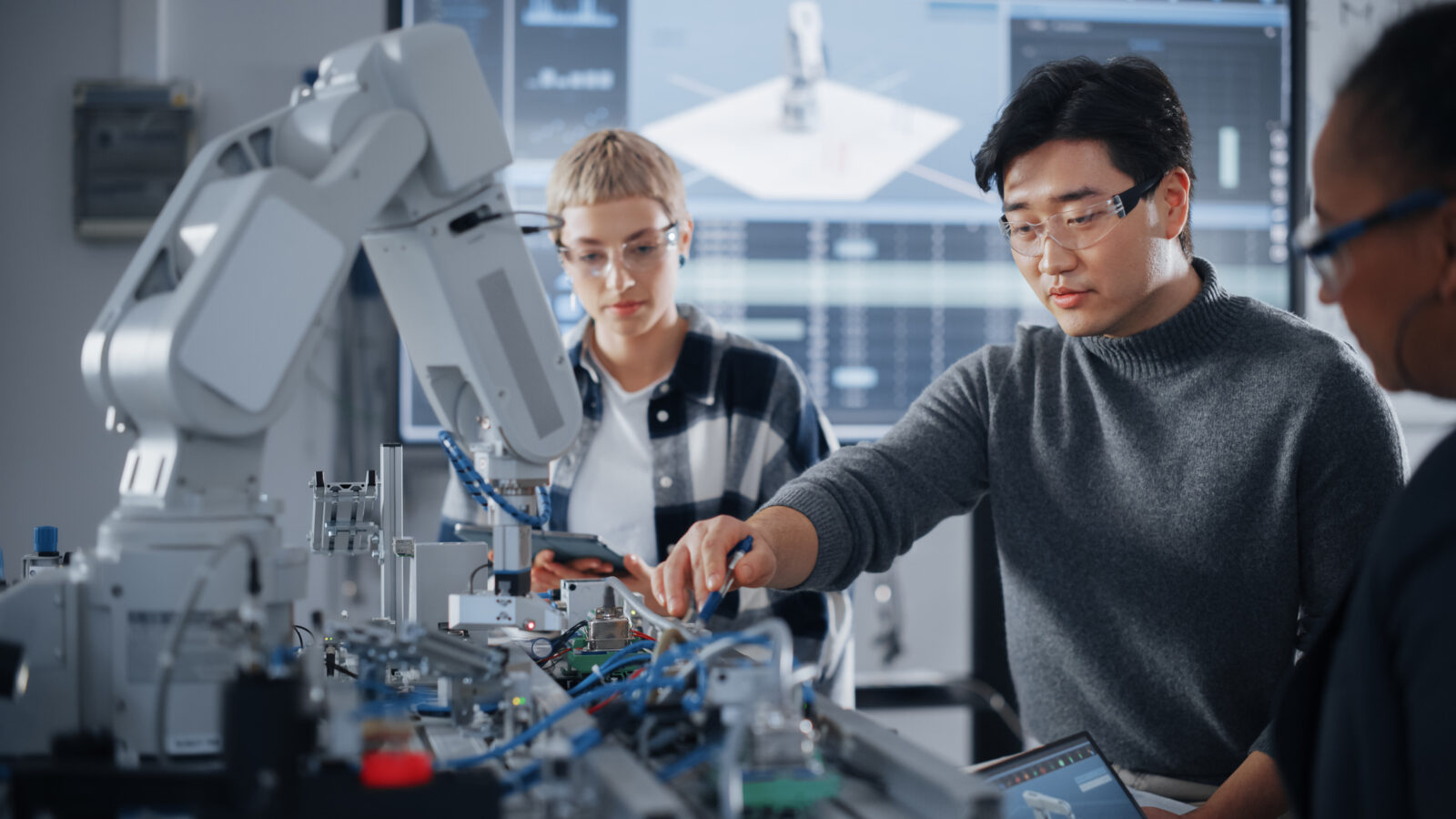 three people learning how to use a complex robot
